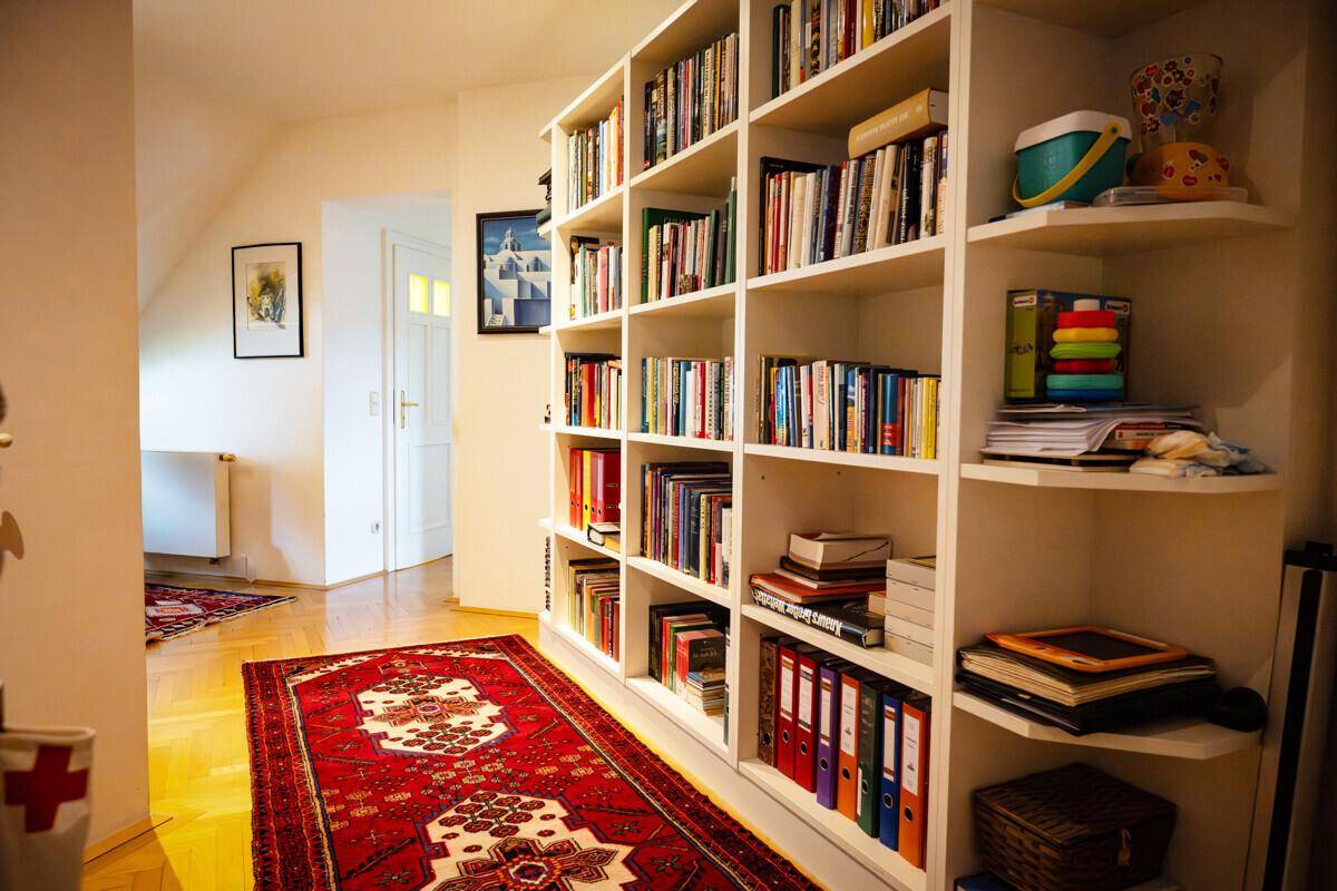 Heller Flur mit großem Bücherregal, Teppich und Parkettboden, der zum Lesen einlädt.