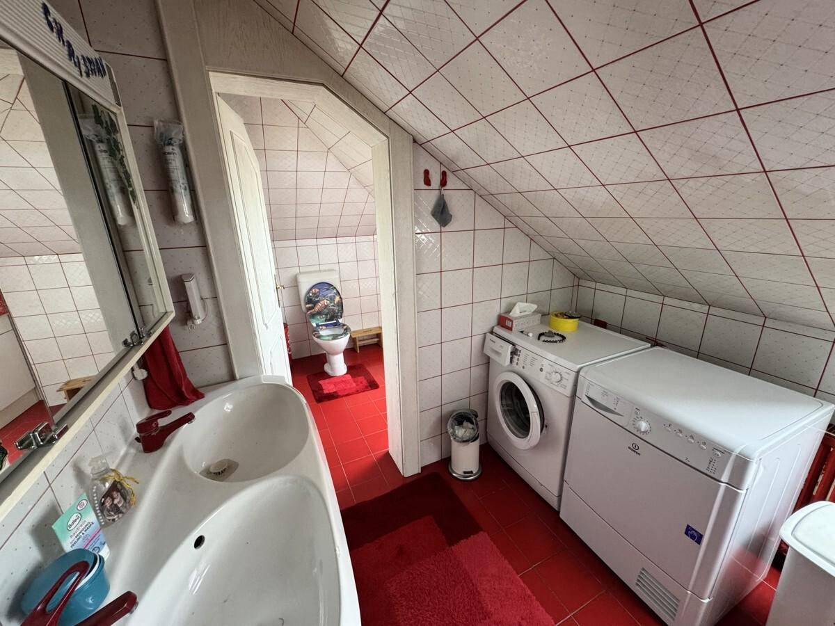 Badezimmer im Dachgeschoss mit Waschmaschine, Trockner und roten Fliesen.
