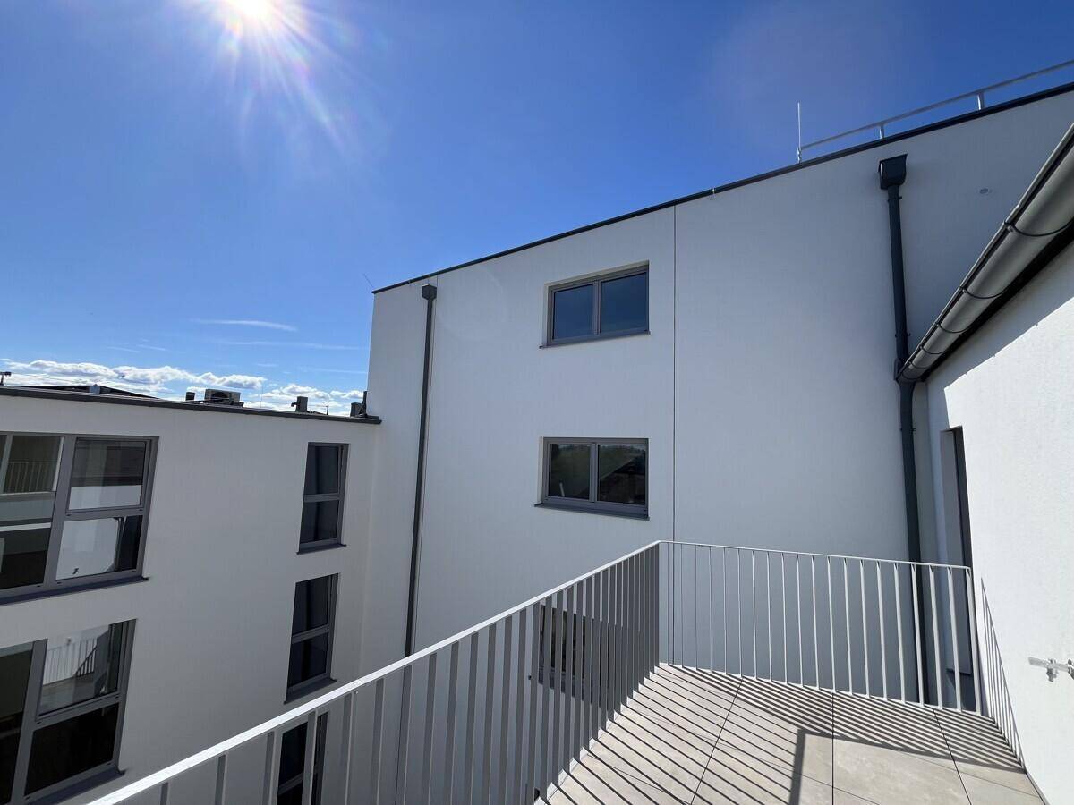 Balkon eines Neubaus mit moderner Architektur und Blick auf die umliegenden Gebäude.