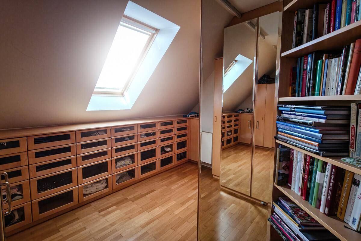 Heller Ankleidebereich im Dachgeschoss mit Einbauschränken, Holzboden und Dachfenster.