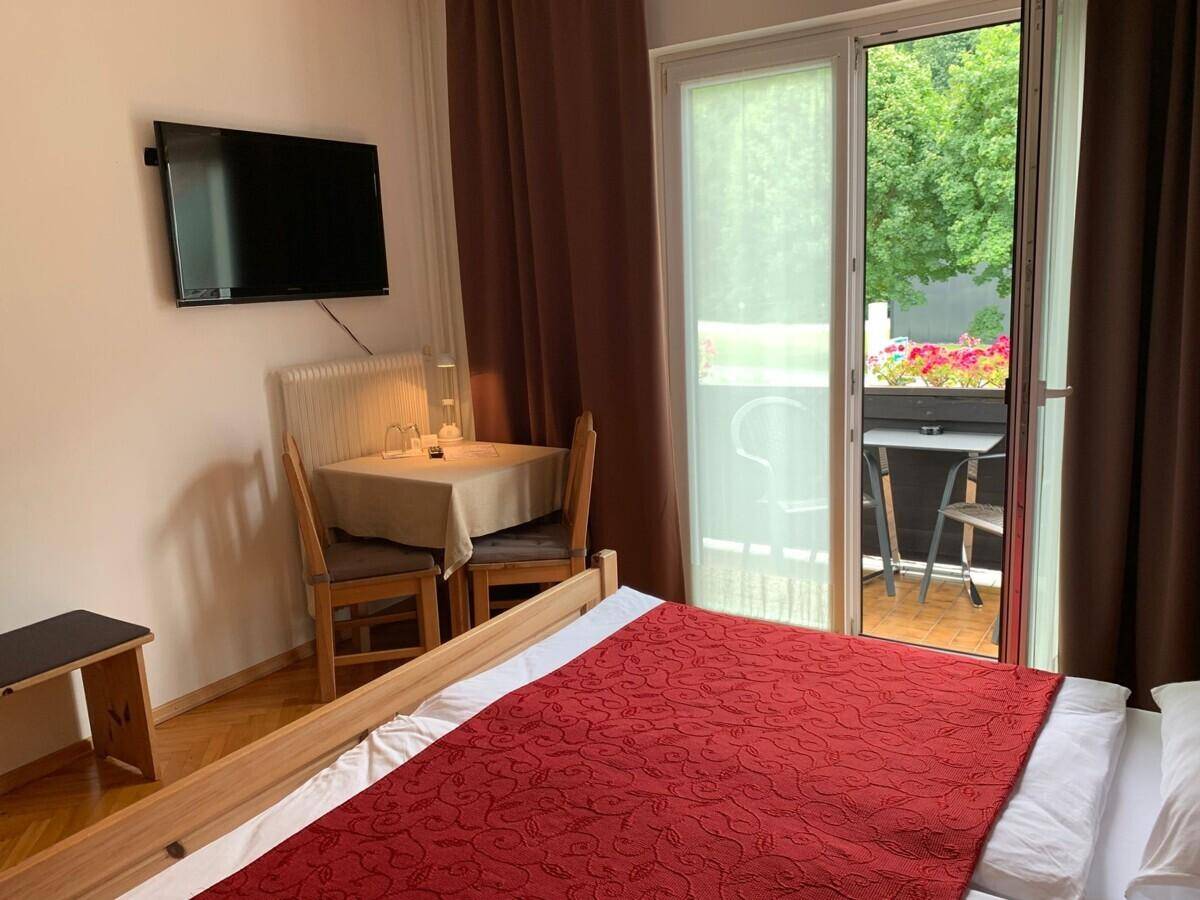 Schlafzimmer mit Doppelbett, kleinem Tisch und direktem Zugang zum Balkon.