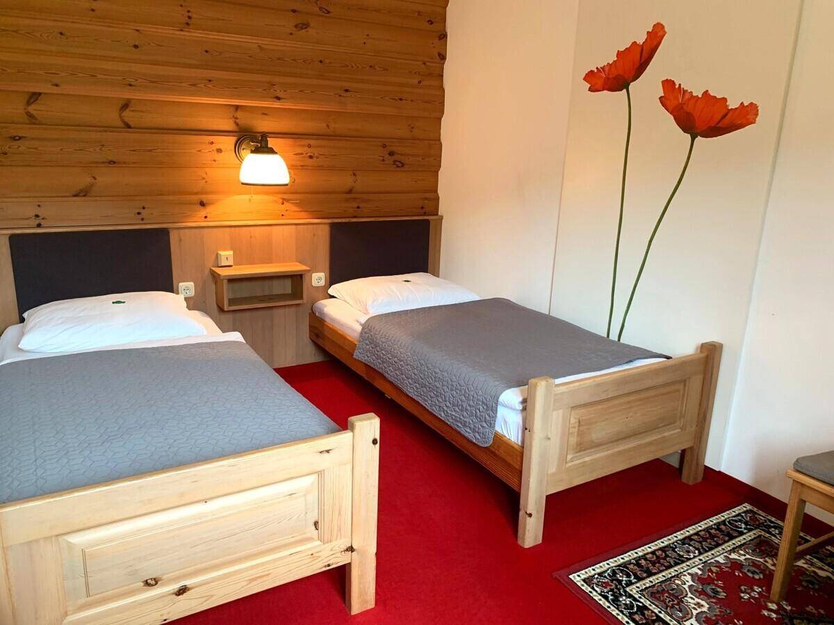 Rustikales Schlafzimmer mit zwei Einzelbetten, Holzvertäfelung und rotem Teppichboden.