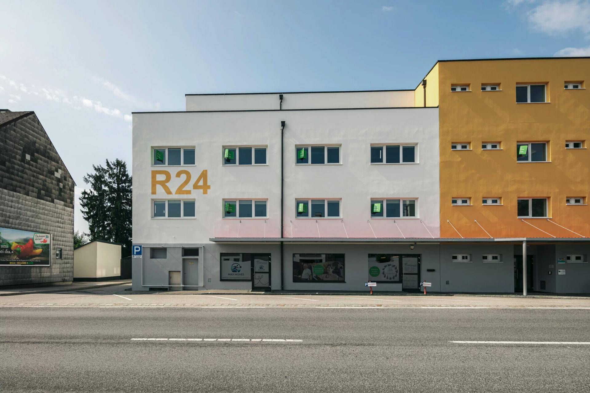 Nahaufnahme der modernen Gebäudefassade mit weißem und gelbem Anstrich und großen Fenstern.