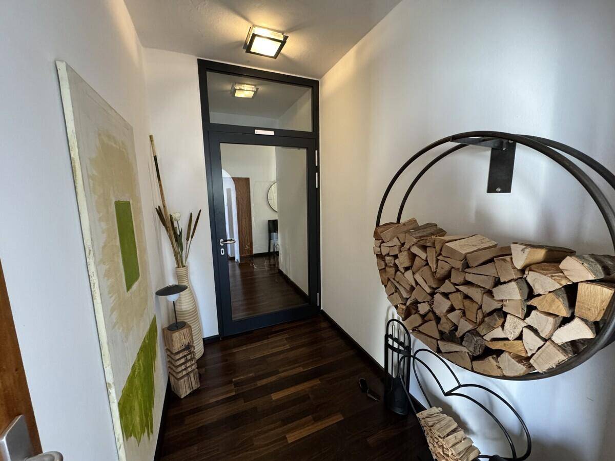 Eingangsbereich mit Holzboden, weiß gestrichenen Wänden und einem dekorativen Holzstapel.