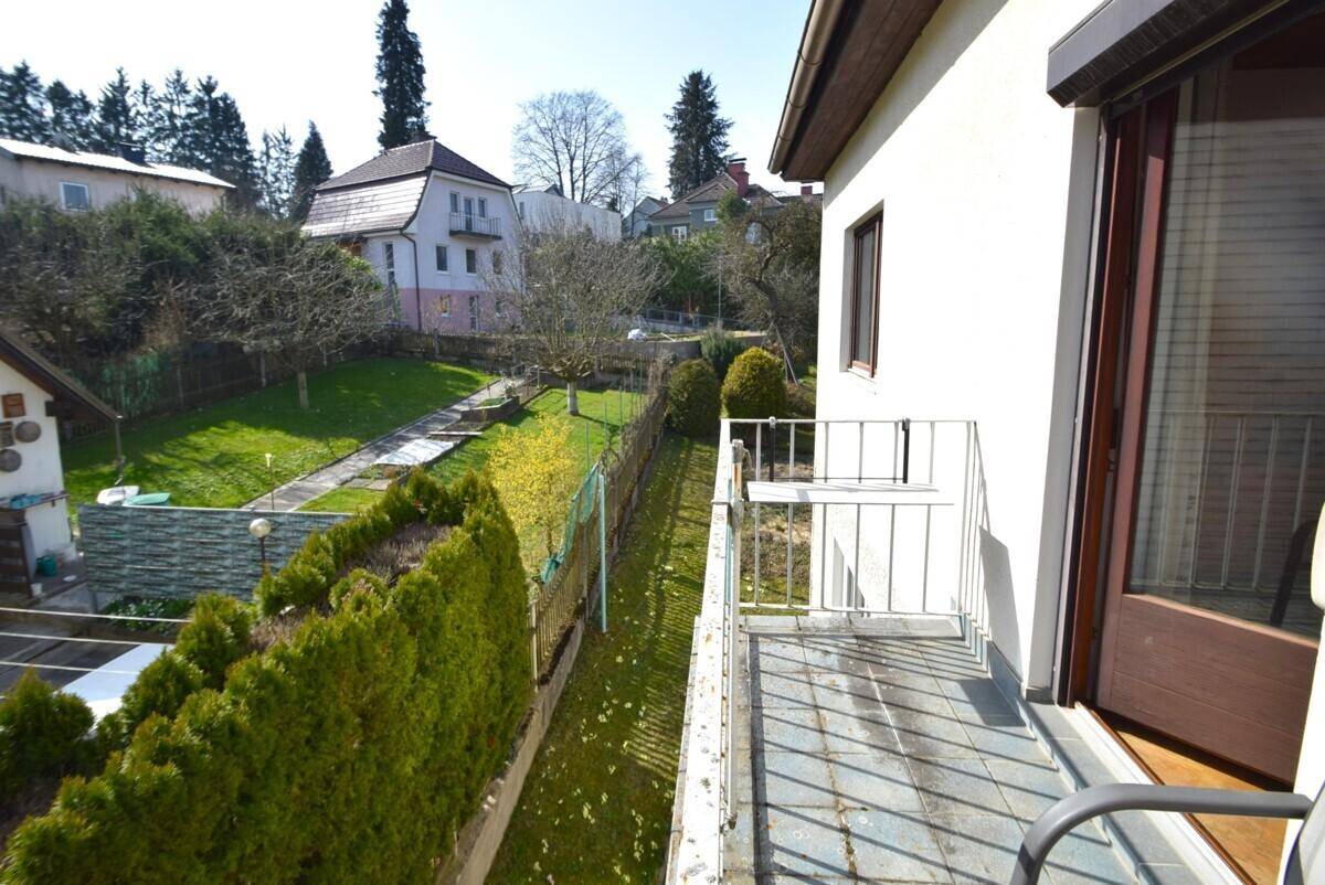 Kleiner Balkon mit Fliesenboden und Blick auf den Garten und die Umgebung.