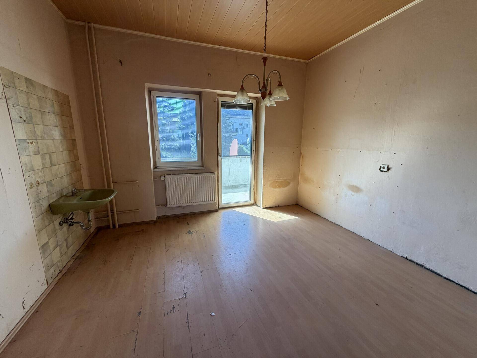 Küche mit Spülbecken und gefliestem Bereich, bereit für eine Modernisierung.