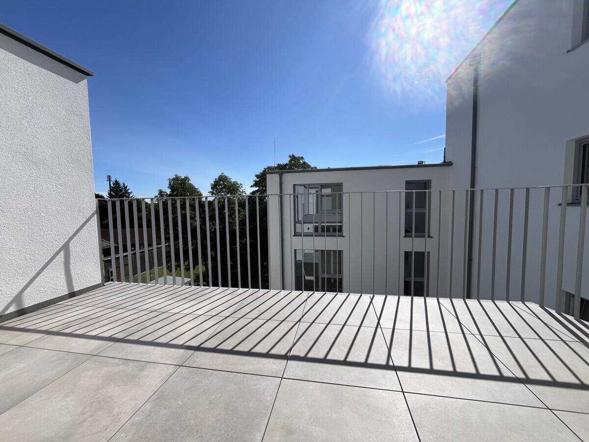 Sonniger Balkon mit Fliesenboden und Metallgeländer, bietet einen Blick auf die Umgebung.