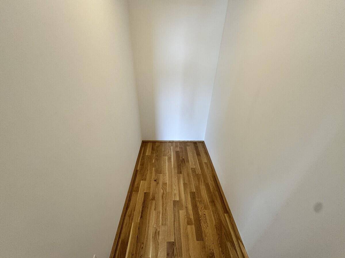 Schmaler, leerer Raum mit Holzboden und weißen Wänden, möglicherweise als Abstellraum nutzbar.