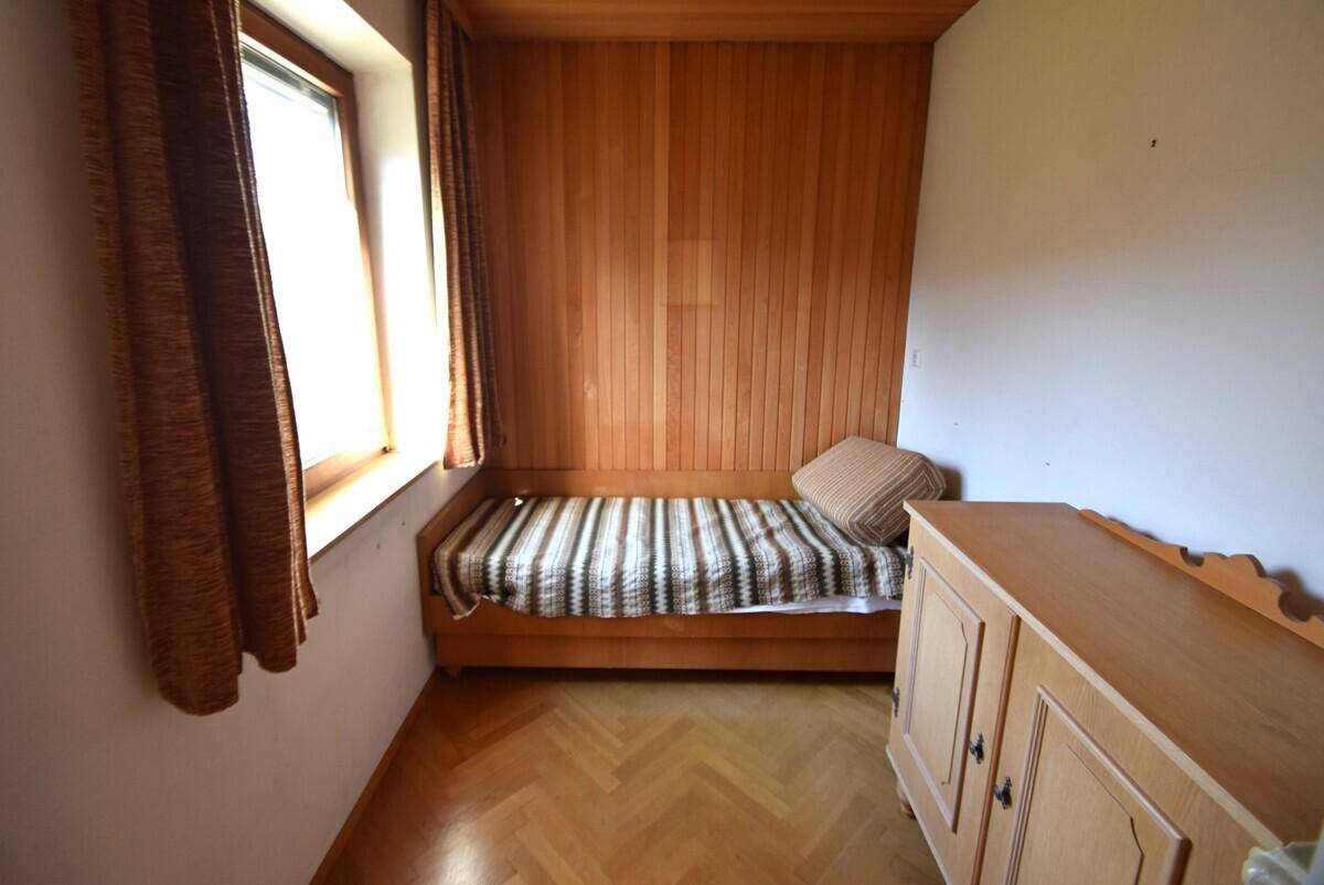 Kleines Schlafzimmer mit Holzparkett, Holzvertäfelung und Tagesbett.