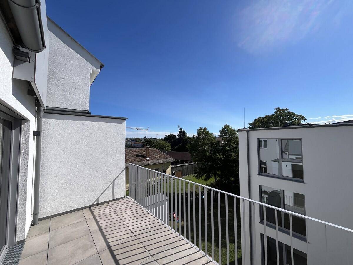 Geräumiger Balkon mit Fliesenboden und weitem Blick über die Nachbarschaft und Bäume.