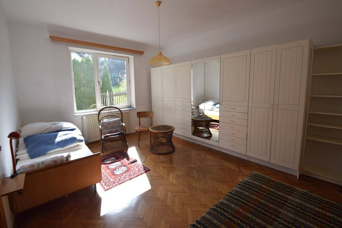 Schlafzimmer mit Holzparkett, großem Spiegelschrank und Blick in den Garten.