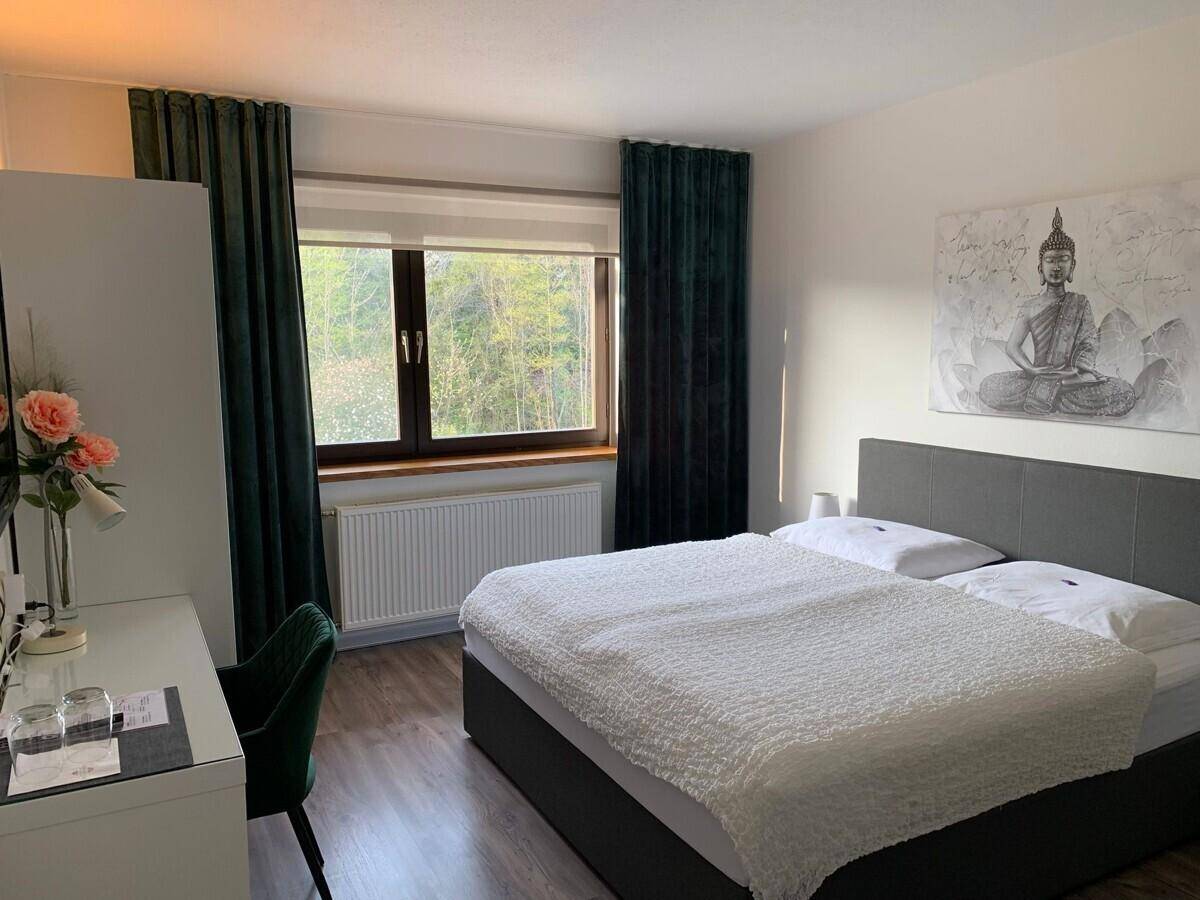 Modern eingerichtetes Schlafzimmer mit Doppelbett, Schreibtisch und Blick ins Grüne.