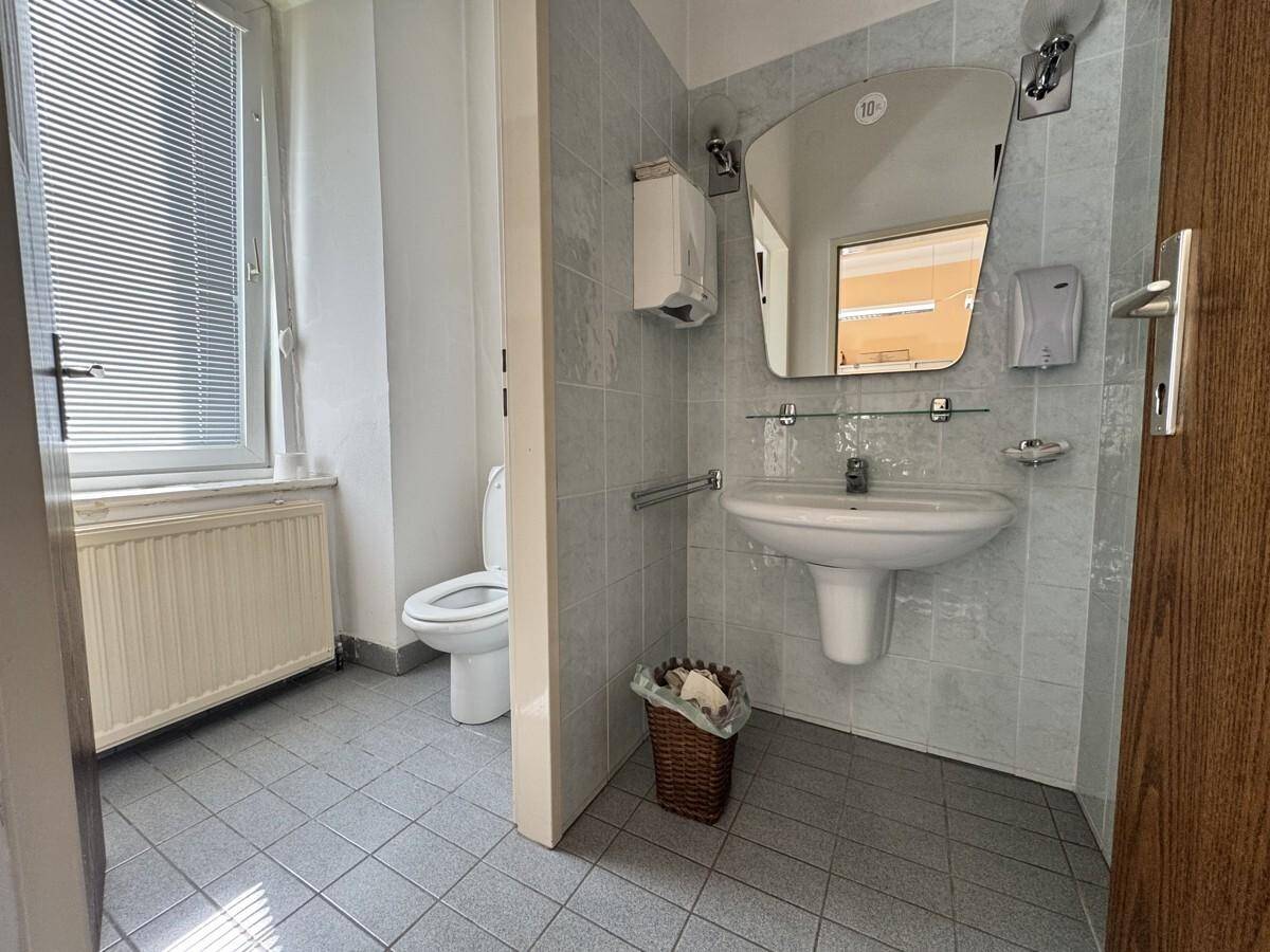 Helles Badezimmer mit WC, Waschbecken, Fliesenboden und einem Fenster für natürliche Belüftung.