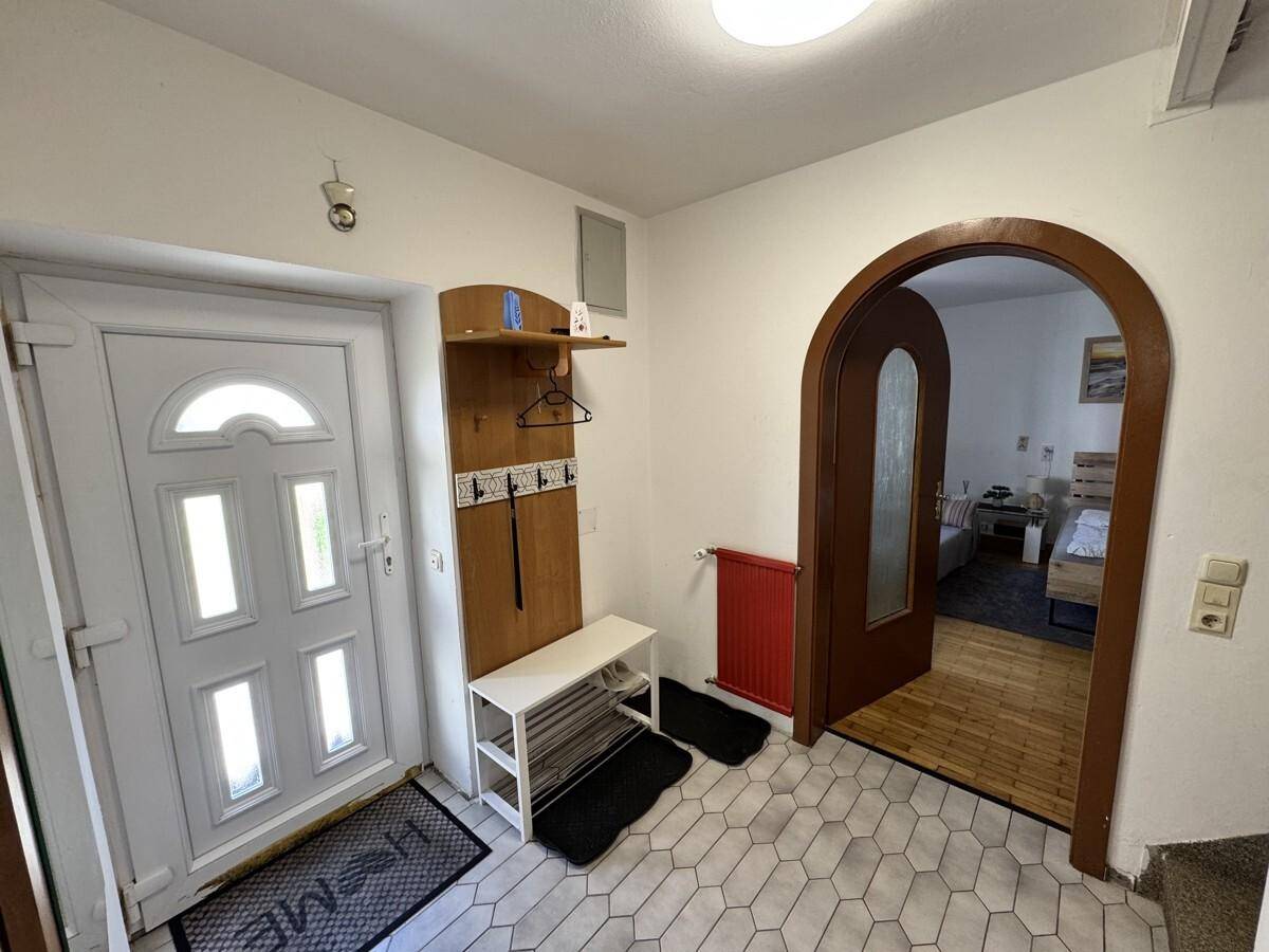 Eingangsbereich mit Fliesenboden, Garderobe und Rundbogen zum Schlafzimmer.