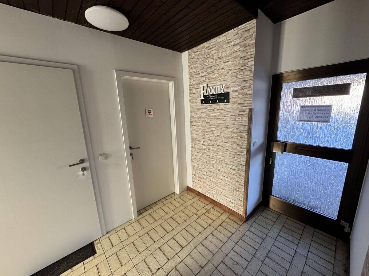 Eingangsbereich mit Fliesenboden, Holztäfelung an der Decke und einer Ziegelwand.