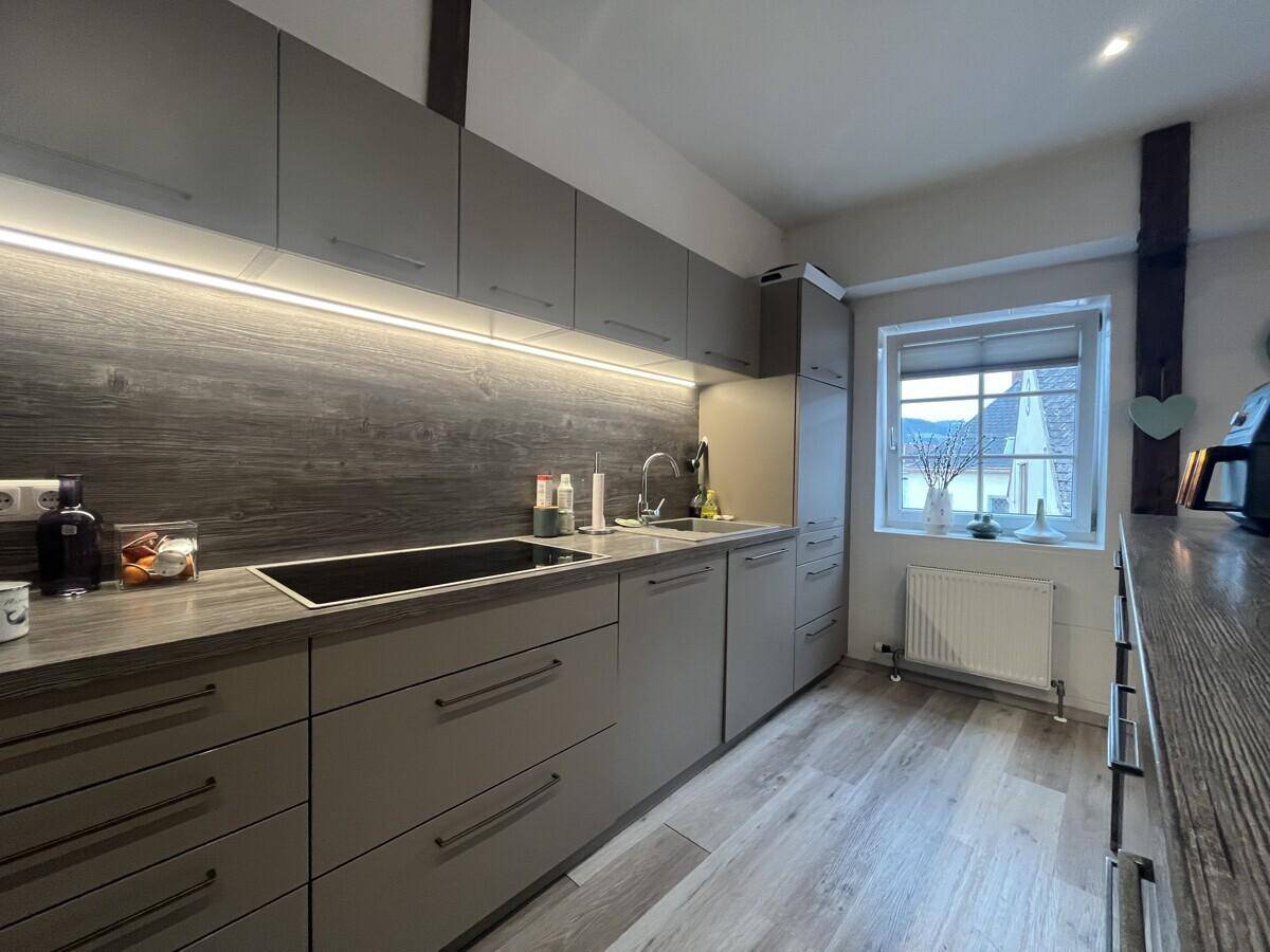 Moderne Küche mit Induktionskochfeld, Spüle und Fenster, ausgestattet mit grauen Schränken.