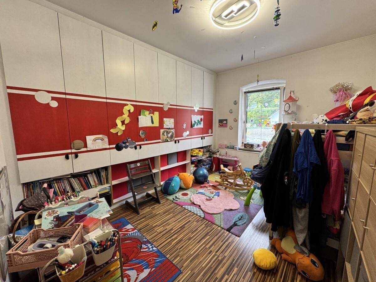 Kinderzimmer mit bunten Dekorationen, viel Stauraum und Holzboden.