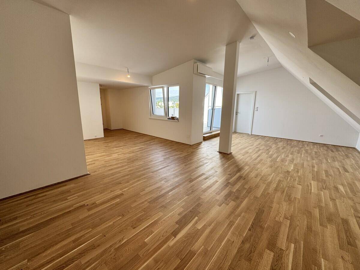 Geräumiger Wohnbereich im Dachgeschoss mit Holzboden und Zugang zur Terrasse.