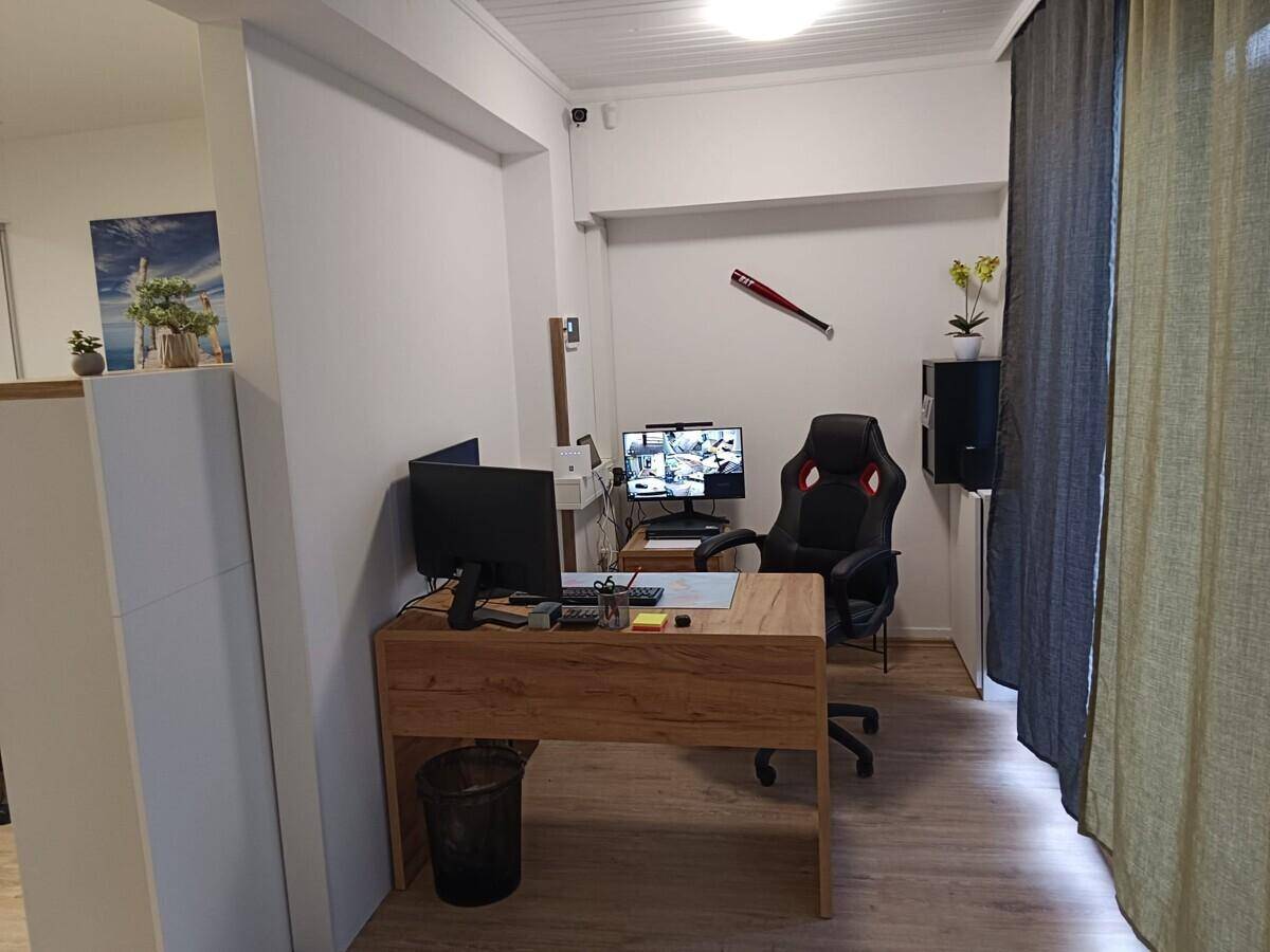 Modern eingerichtetes Büro mit Holztisch, Bürostuhl und Laminatboden.