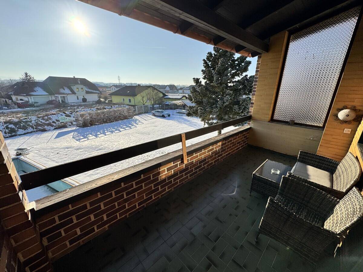 Balkon mit Sitzgelegenheiten und Blick auf den Garten und die verschneite Umgebung.
