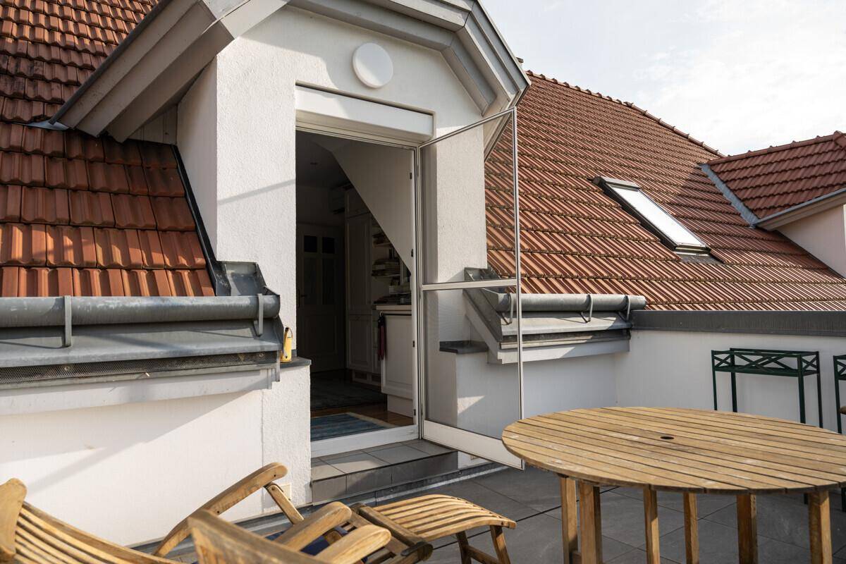 Geräumige Dachterrasse mit Holztisch und Stühlen, ideal für entspannte Stunden im Freien.