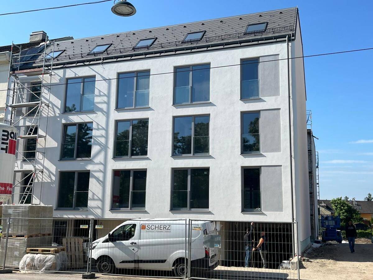 Nahaufnahme der modernen Fassade eines Neubaus mit großen Fenstern und Dachgauben.
