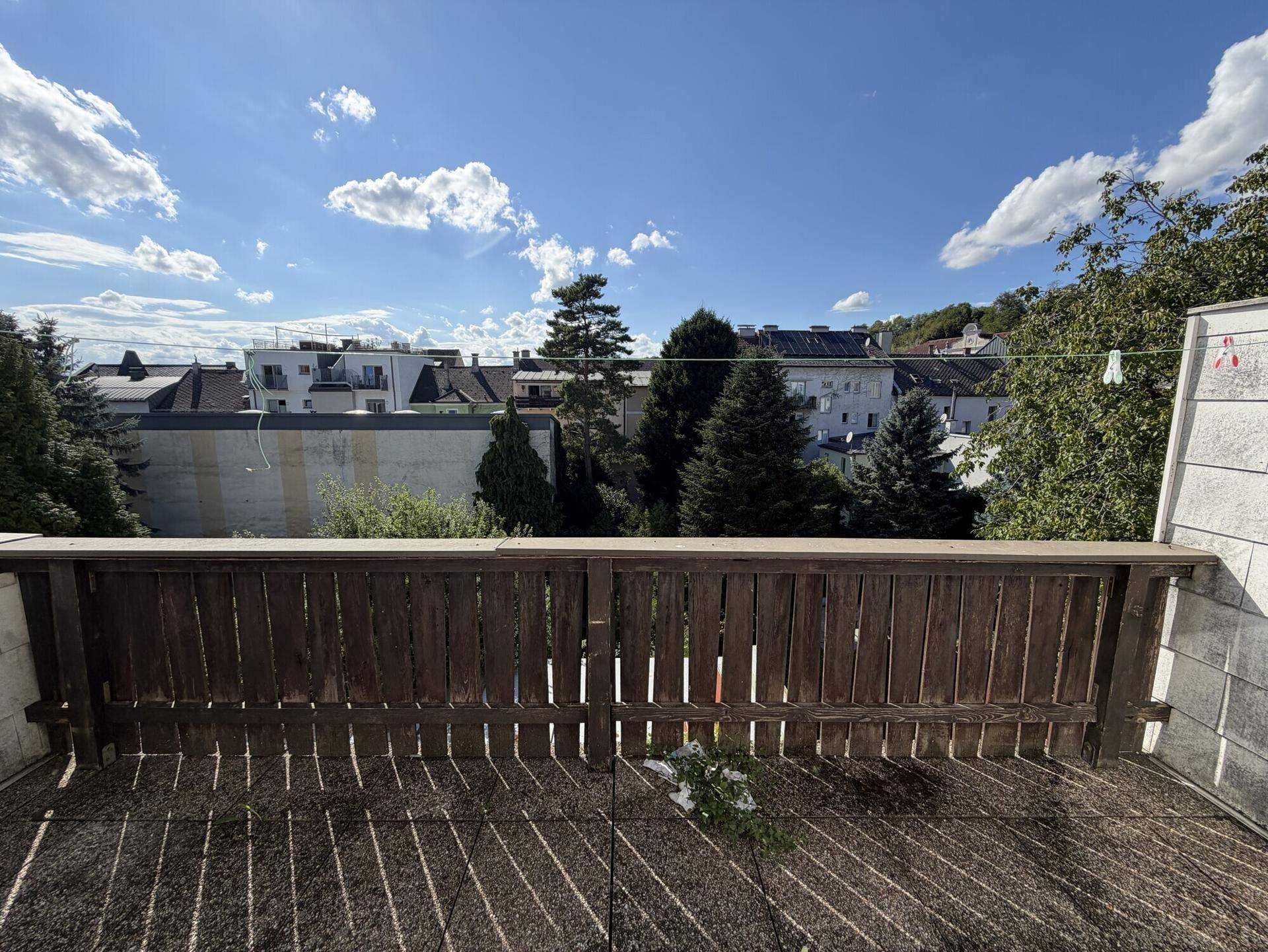 Großer Balkon mit Holzboden und weitem Blick über die Dächer der Stadt.