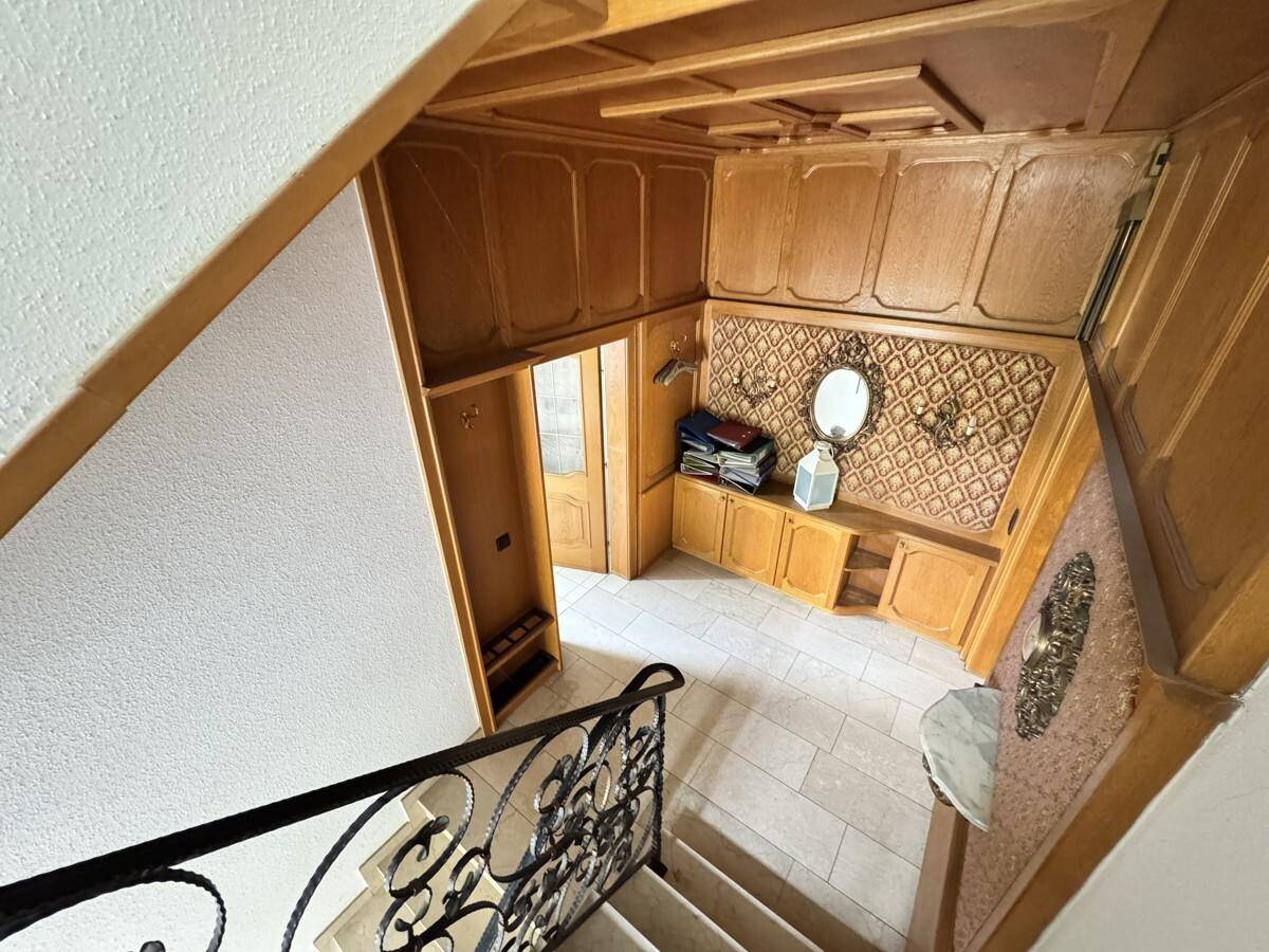 Eingangsbereich mit Holzvertäfelung, gefliestem Boden und schmiedeeisernem Treppengeländer.