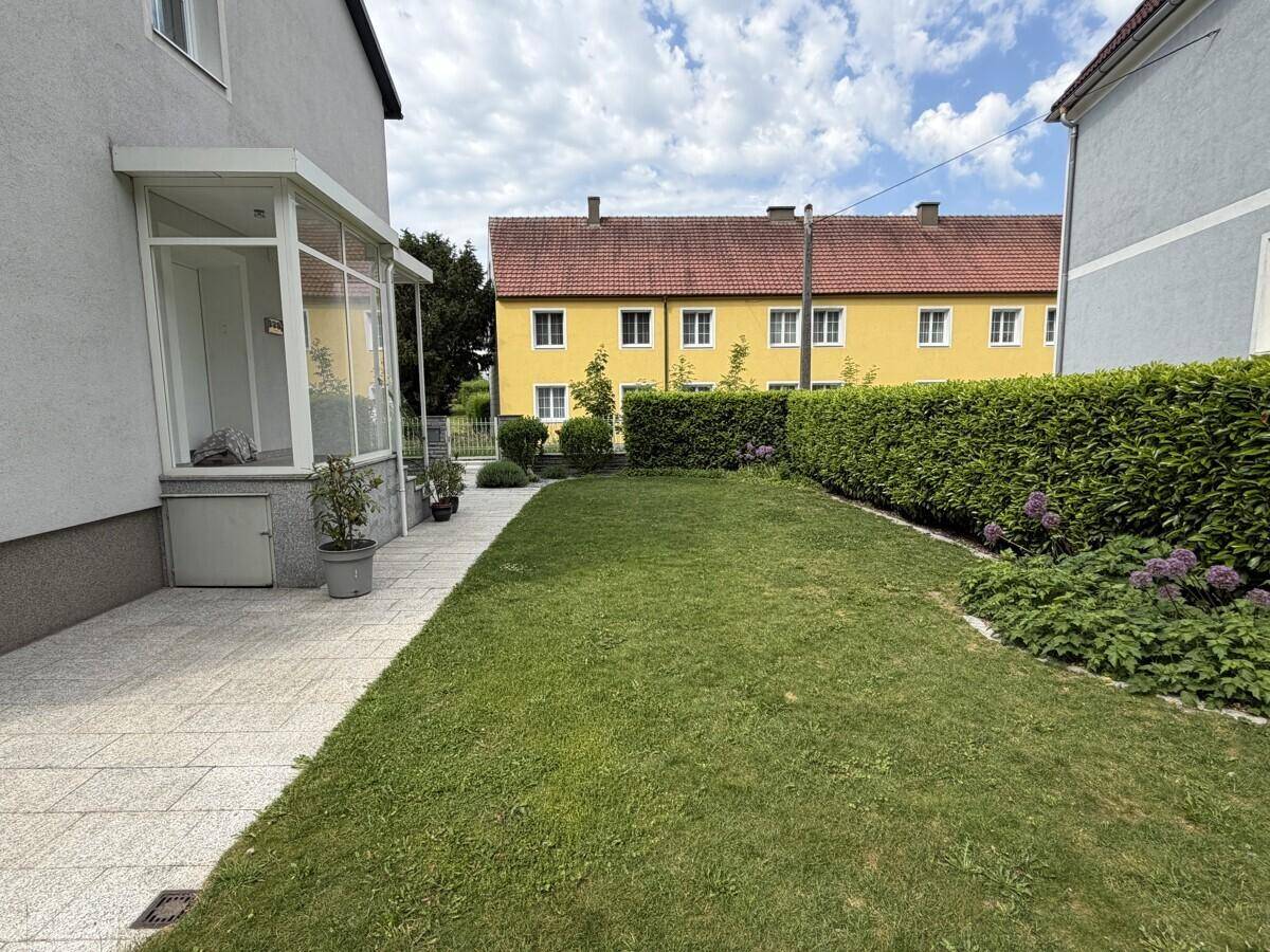Großer, sonniger Garten mit Rasenfläche und Hecken, ideal für Erholung im Freien.
