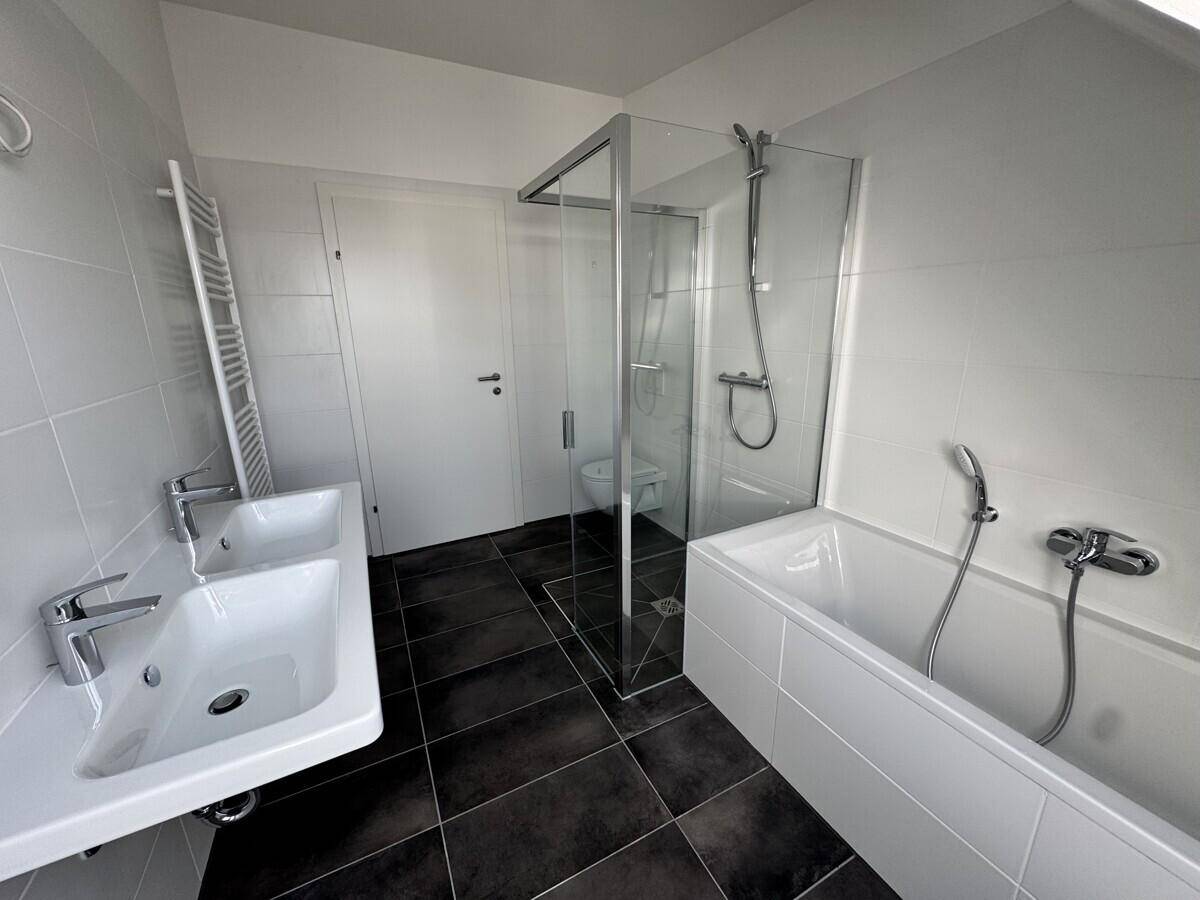 Modernes Badezimmer mit Badewanne, Dusche, Einzelwaschbecken und beheiztem Handtuchhalter.