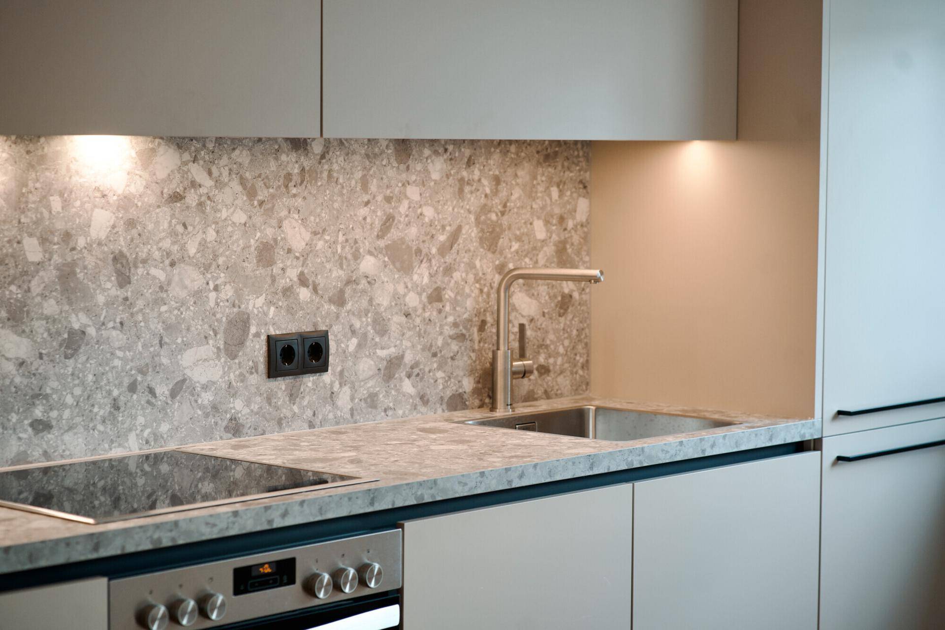Detailansicht der modernen Küche mit Spüle, Induktionskochfeld und Backofen.