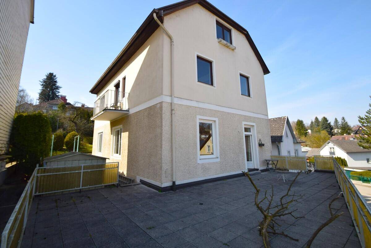 Große gepflasterte Terrasse mit Sitzgelegenheiten und Blick auf das Haus.