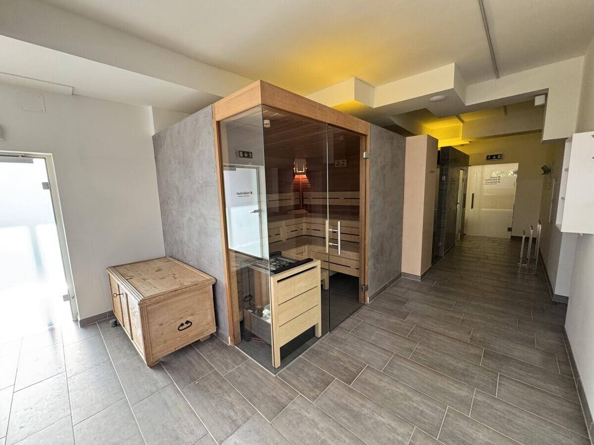 Moderner Wellnessbereich mit Sauna, Infrarotkabine und Umkleidekabinen, in hellen Farben gehalten.