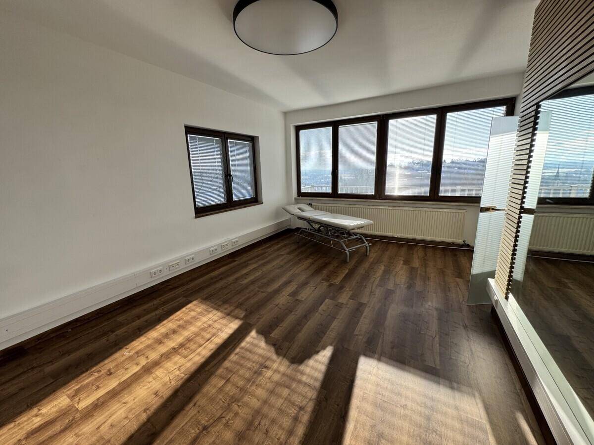 Geräumiger Büroraum mit Laminatboden und großen Fenstern, die viel Tageslicht und eine weite Aussicht bieten.