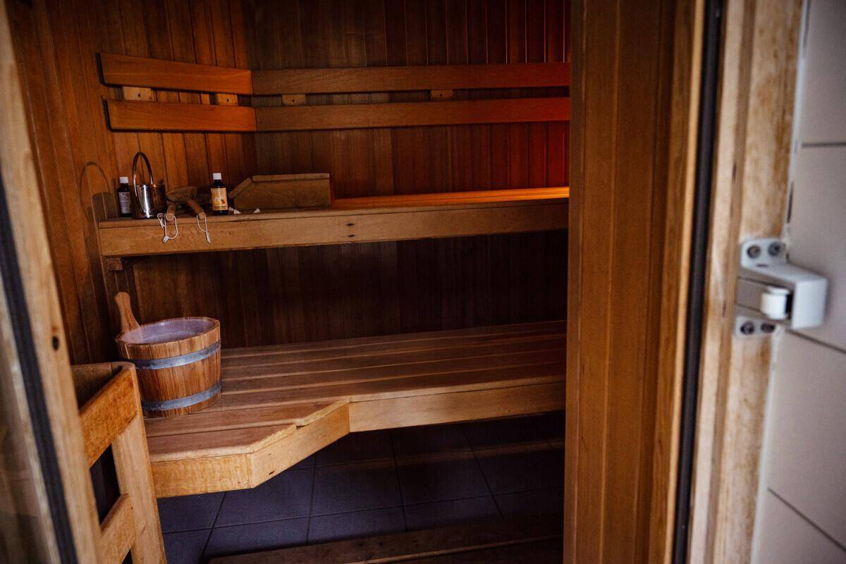 Traditionelle Holzsauna mit Bänken und Eimer für entspannende Wellness-Momente.