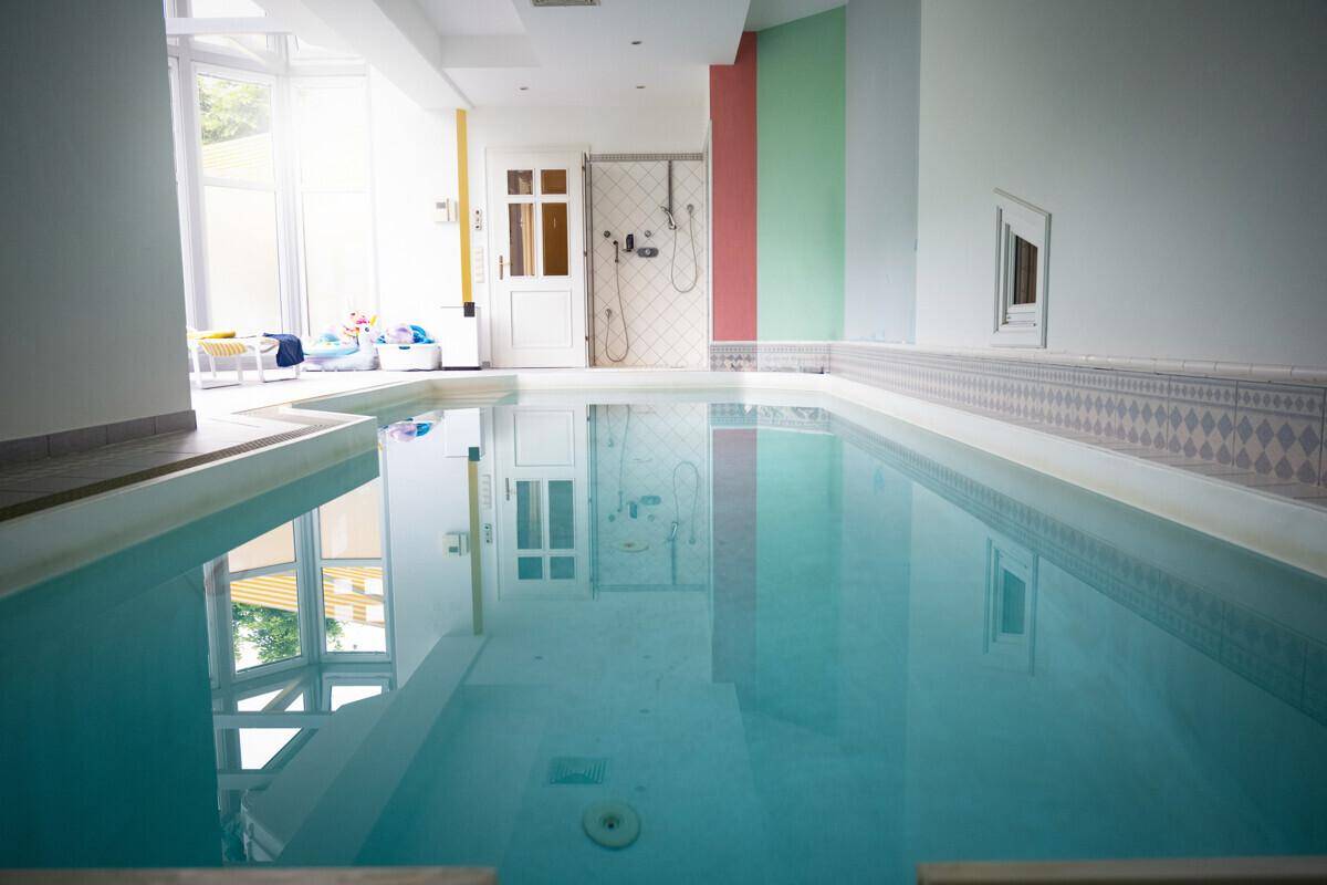 Großes Hallenbad mit viel Tageslicht und farbigen Wänden für entspannte Stunden.