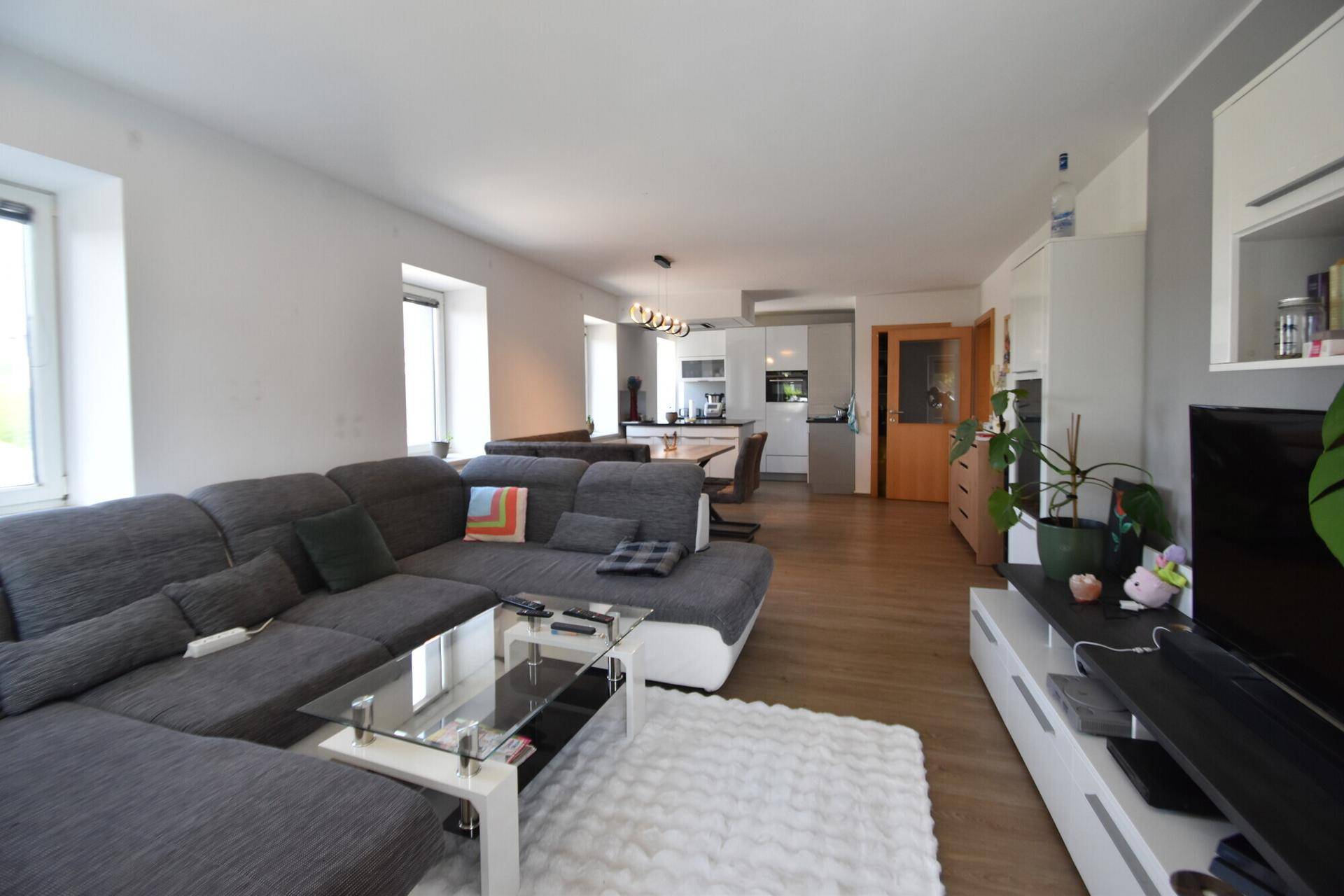 Geräumiger Wohnbereich mit großem Ecksofa, Couchtisch und Blick in die offene Küche.