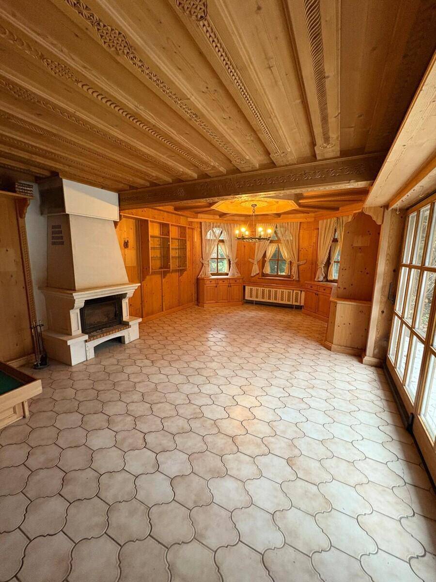Heller Wohnraum im alpinen Stil mit Holzwänden, Kamin und großen Fenstern.