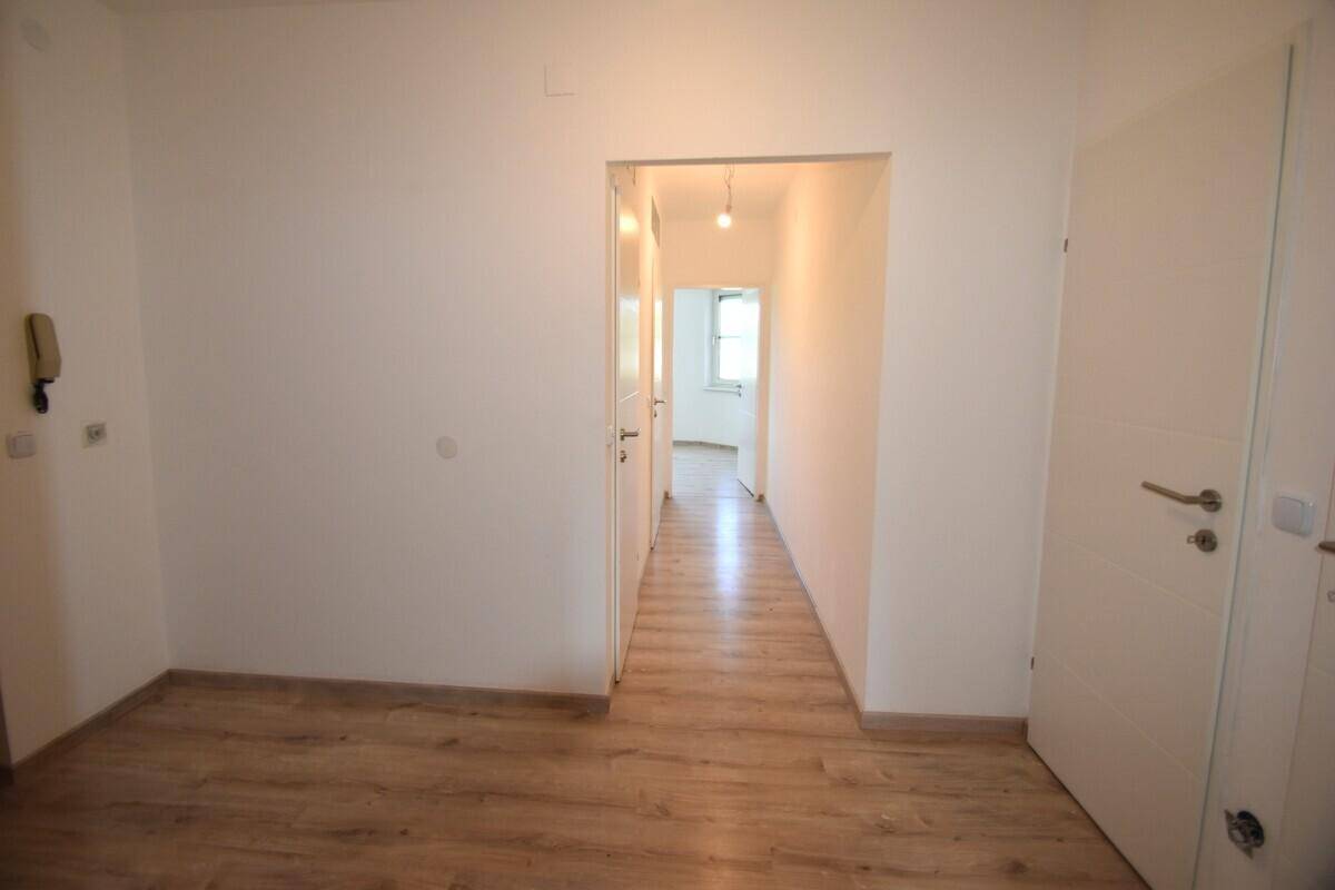 Heller Flur mit Laminatboden und weißen Türen, der zu weiteren Räumen der Wohnung führt.