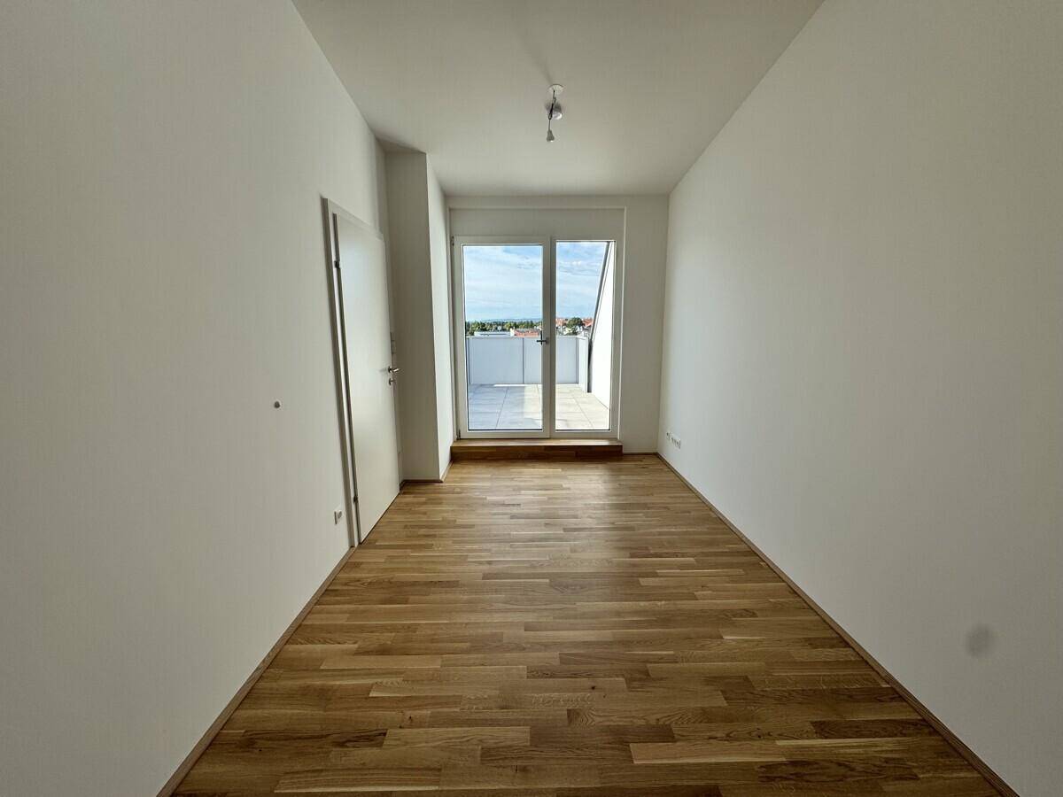 Helles Schlafzimmer mit Holzboden und direktem Zugang zur Dachterrasse.