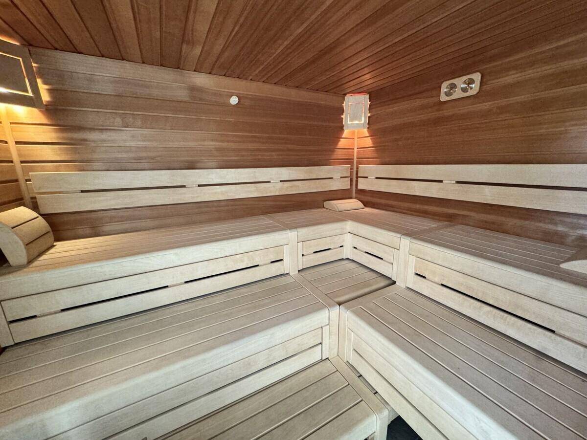 Geräumige Holzsauna mit mehrstufigen Bänken und indirekter Beleuchtung, für Entspannung.