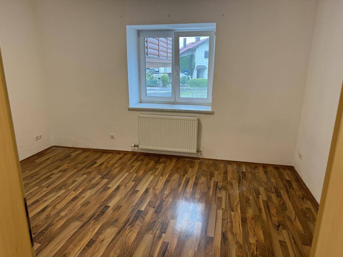 Leeres Zimmer mit Laminatboden und Fenster zur Straße, bereit zur individuellen Gestaltung.