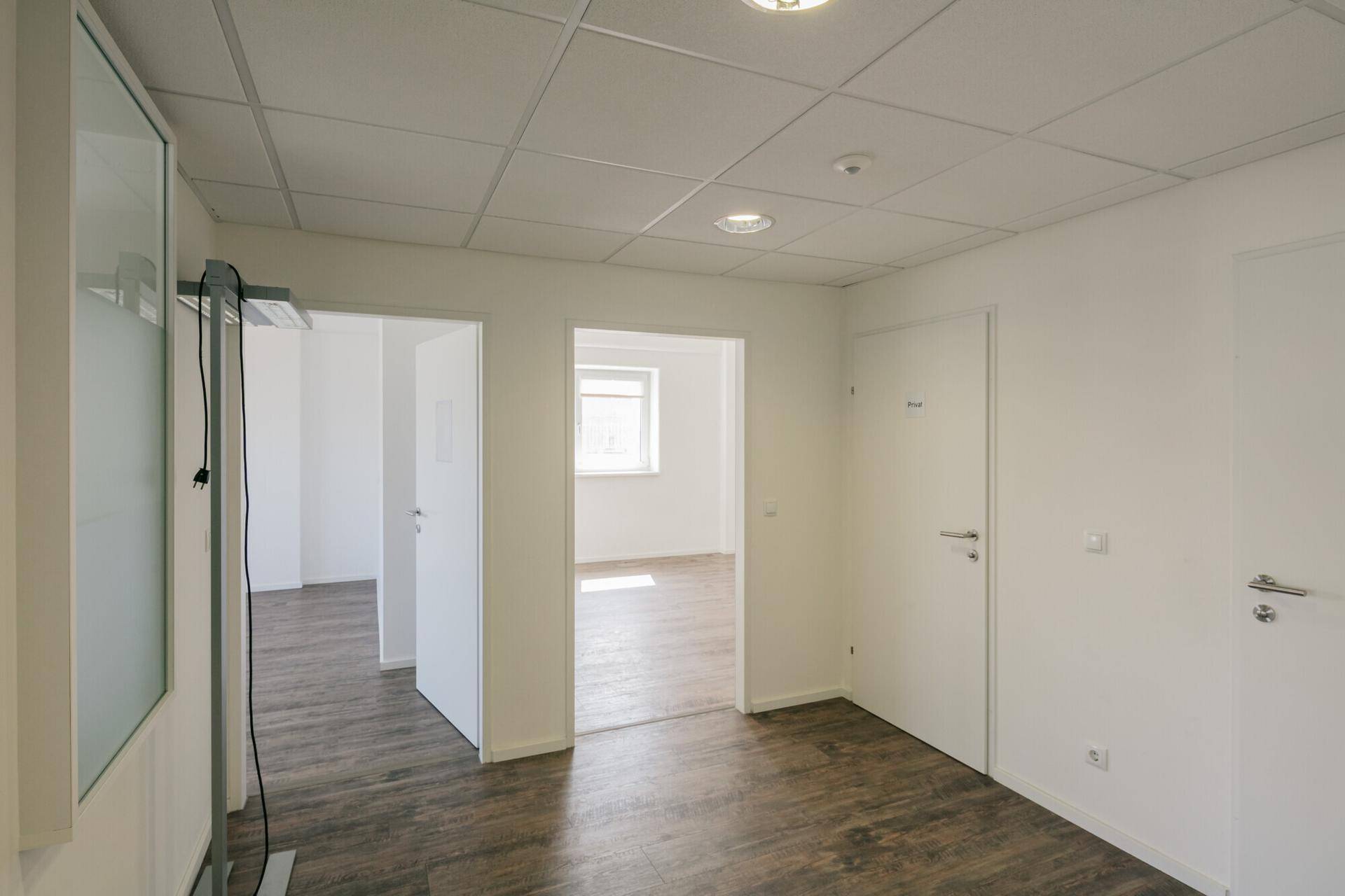 Heller Flur mit Holzoptik-Boden und mehreren Türen, die zu den angrenzenden Büroräumen führen.