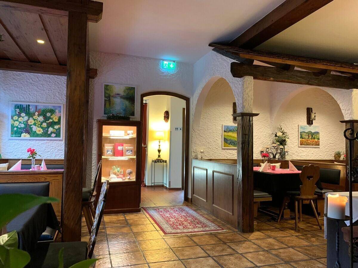 Gemütlicher Restaurantbereich mit Holzelementen, Nischen und Durchgang zu weiteren Räumen.