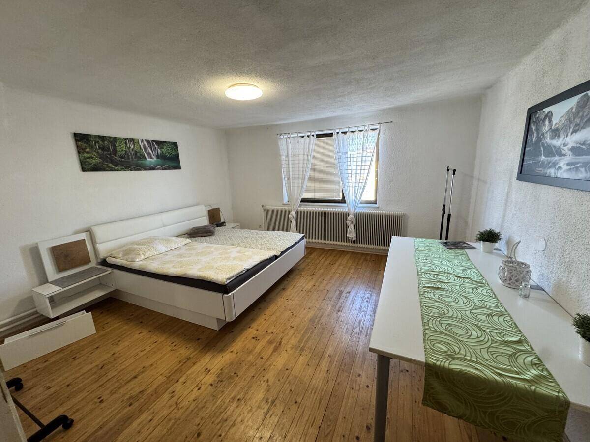 Geräumiges Schlafzimmer mit Doppelbett, Holzboden und Blick ins Grüne.