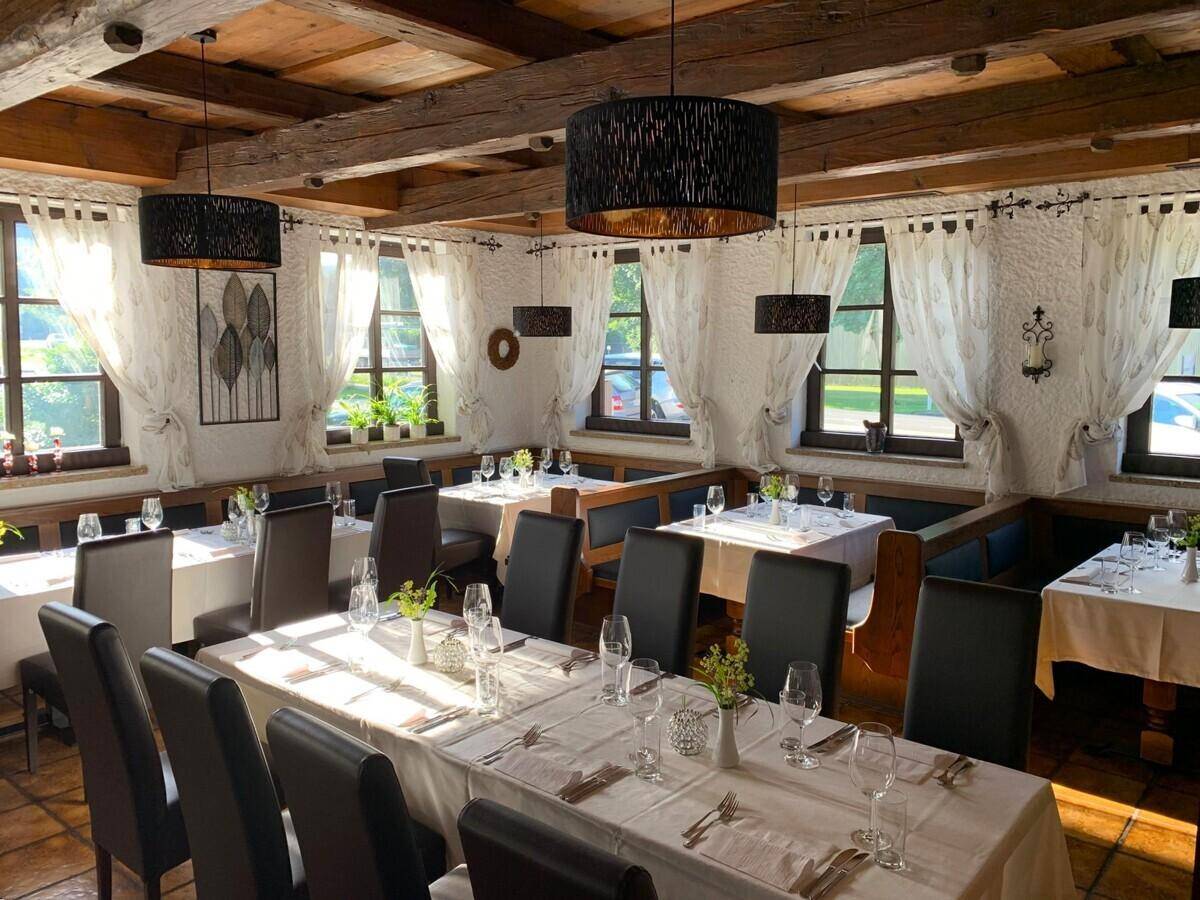 Heller Speisesaal mit Holzbalkendecke, rustikalen Wänden und elegant gedeckten Tischen.