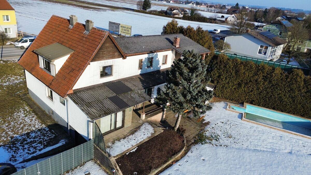 Seitenansicht des Hauses mit Satteldach, Anbau und Poolbereich im winterlichen Garten.