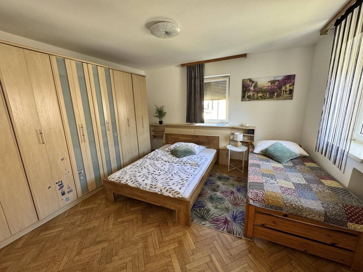 Schlafzimmer mit zwei Einzelbetten, großem Kleiderschrank und Parkettboden.