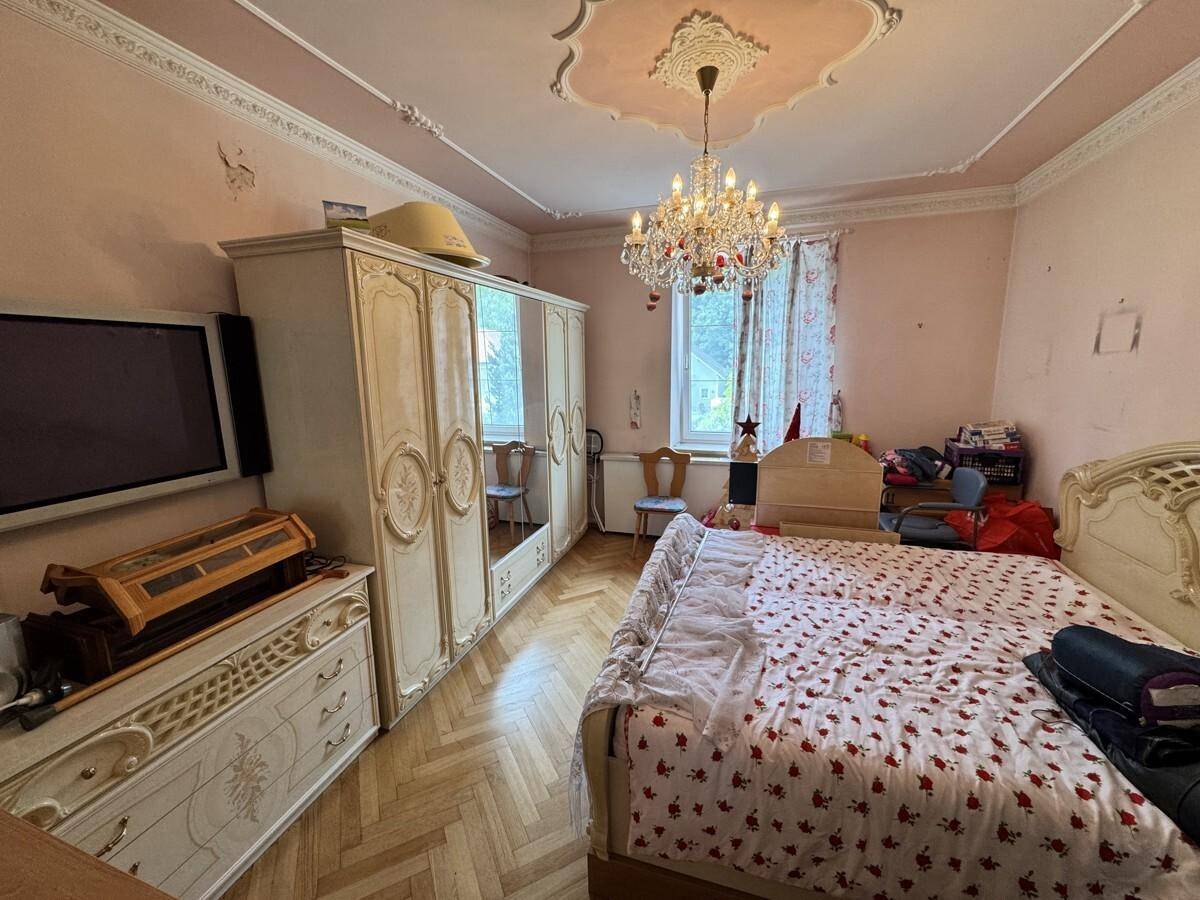 Schlafzimmer im klassischen Stil mit Stuckdecke, Kronleuchter und Parkettboden.