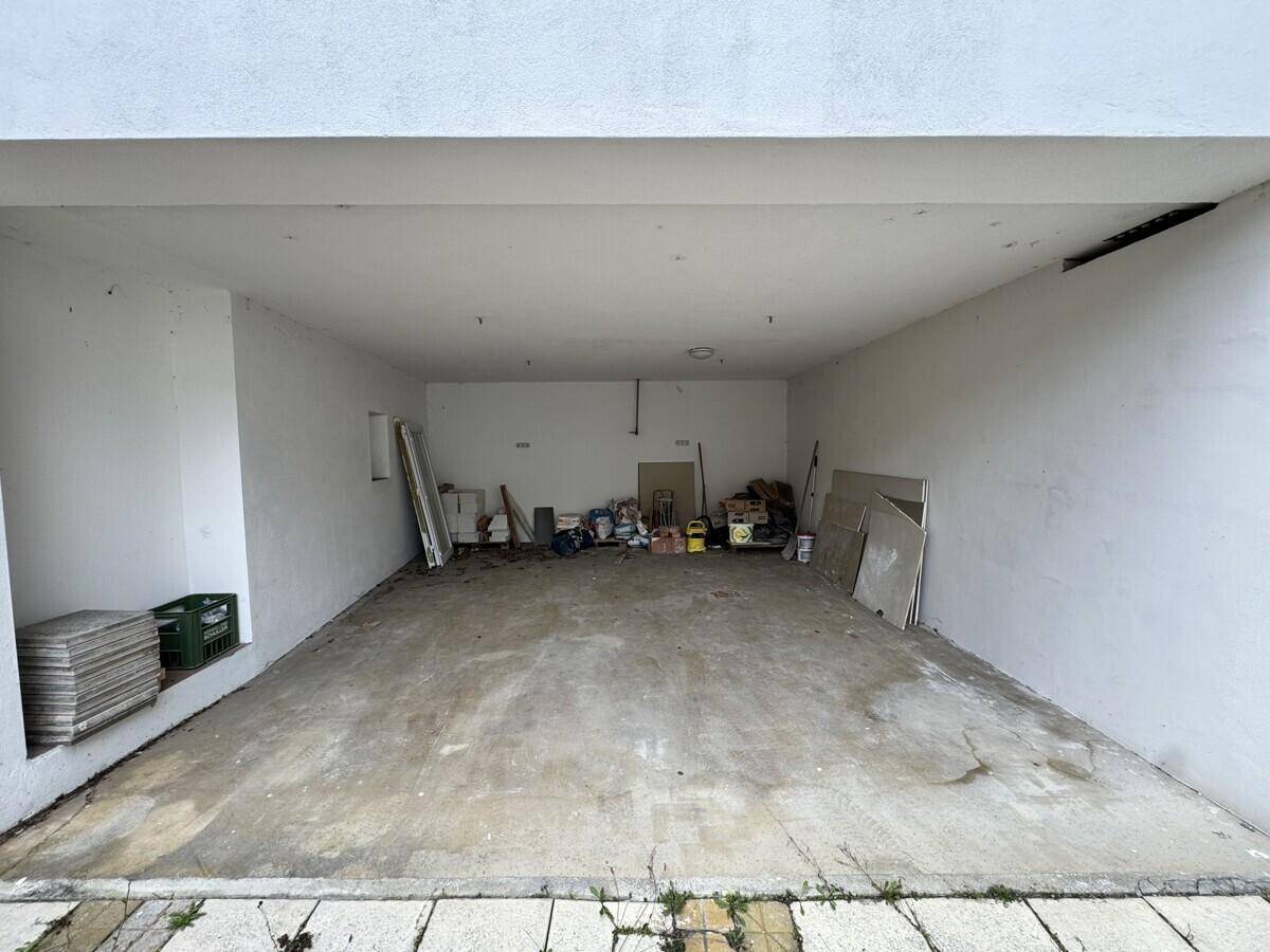 Offener Garagenbereich mit Betonboden und Stauraum an den Seitenwänden.